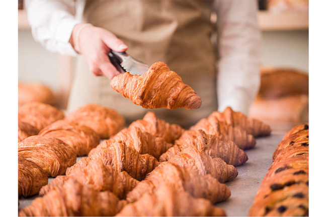 Bridor employee holds croissant.