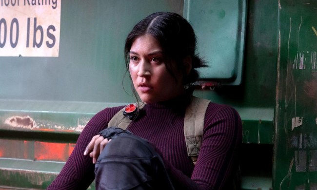 Maya from the MCU series Echo on Hulu sitting in a chair, her leg up.