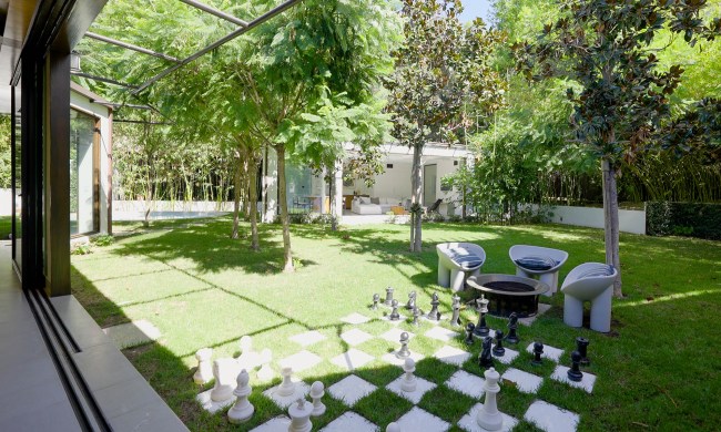 A grassy backyard that has a life-sized chess game.