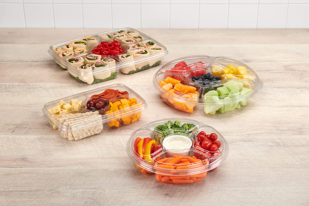 plastic party trays with fruit, vegetables, and wraps