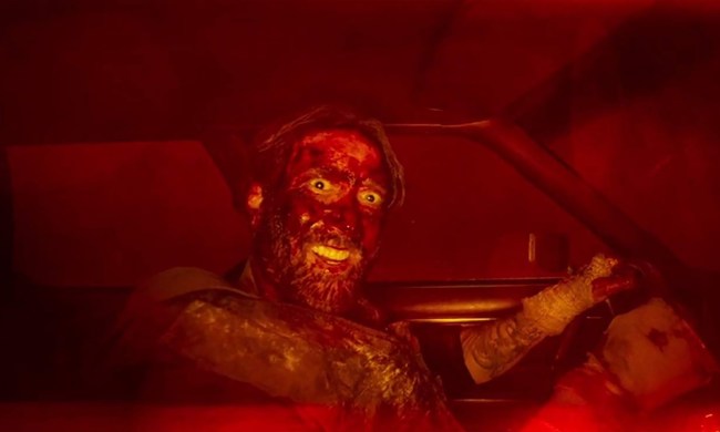 A bloody Nicolas Cage smiles in a car in Mandy.