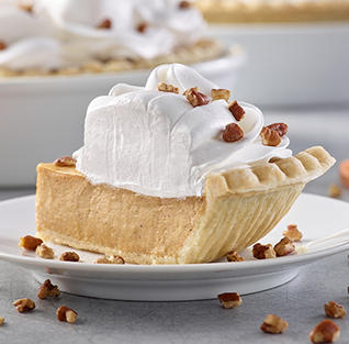 A pie with whipped cream and pecans on a plate

Description automatically generated